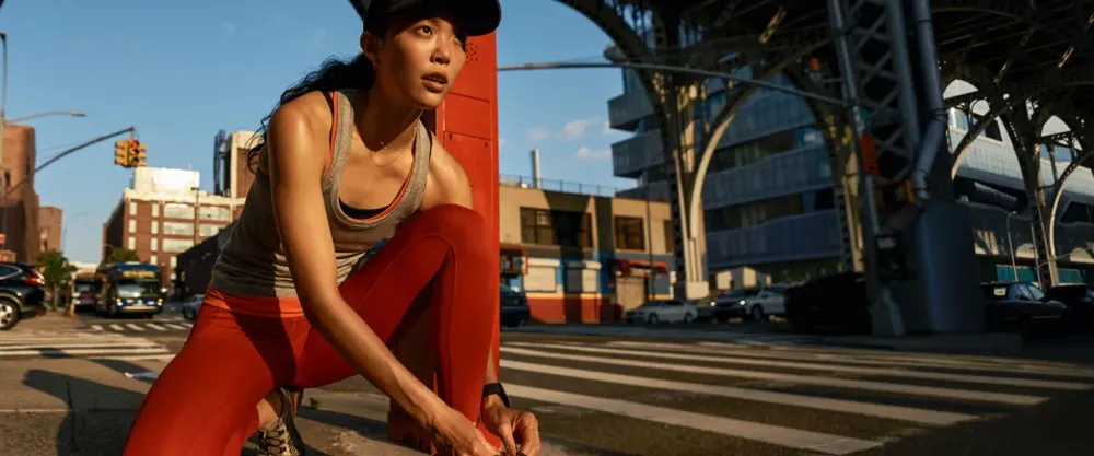 Woman kneeling to tie her shoes in street wearing lululemon gear